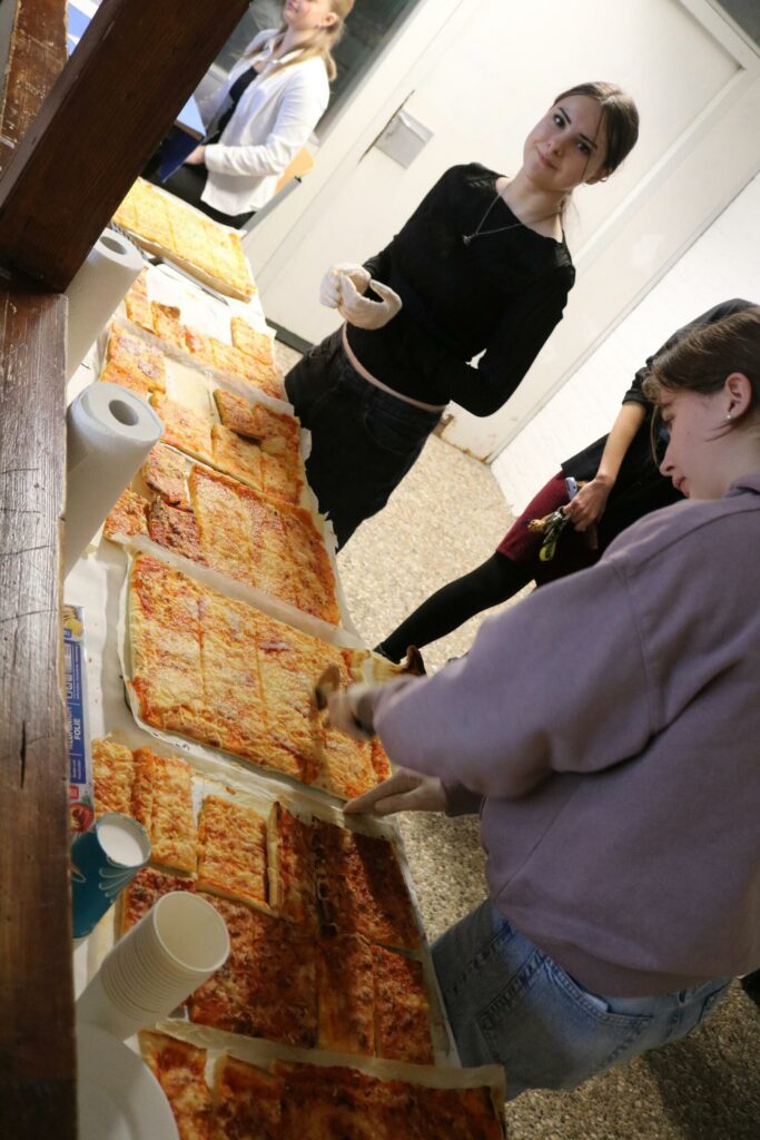 Schülerinnen verteilen Pizzastücke an einem Tisch.