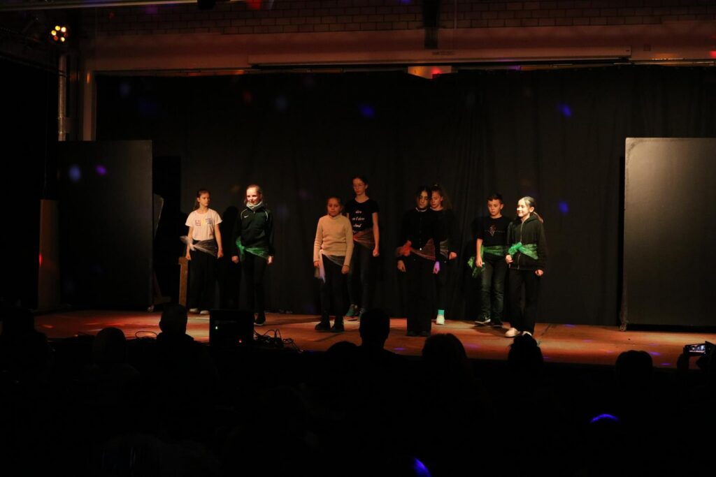 Schüler führen auf einer Bühne ein Theaterstück vor.