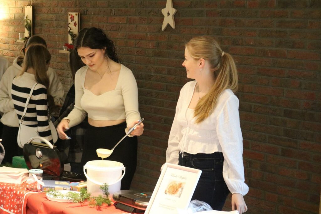 Zwei Frauen an einem Stand mit Speisen und Getränken.