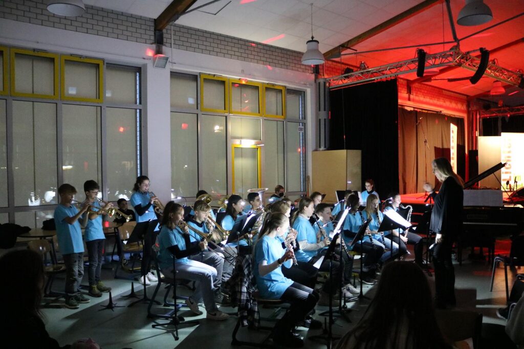 Schüler spielen in blauen T-Shirts in einem Orchester während eines Konzerts.