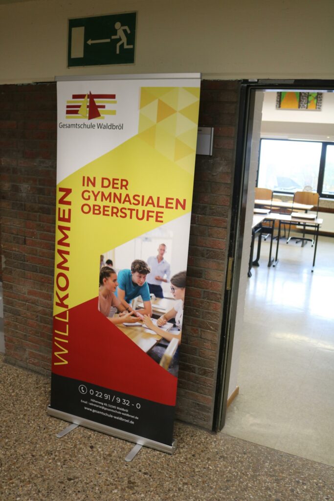 Rollup-Banner mit der Aufschrift "Willkommen in der Gymnasialen Oberstufe" und Bildern von Schülern.