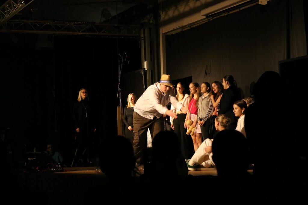 Eine Theateraufführung mit mehreren Darstellern auf der Bühne.