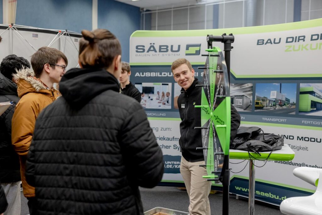Schüler am Stand von Säbu, wo ein Mitarbeiter ein Rad zeigt.