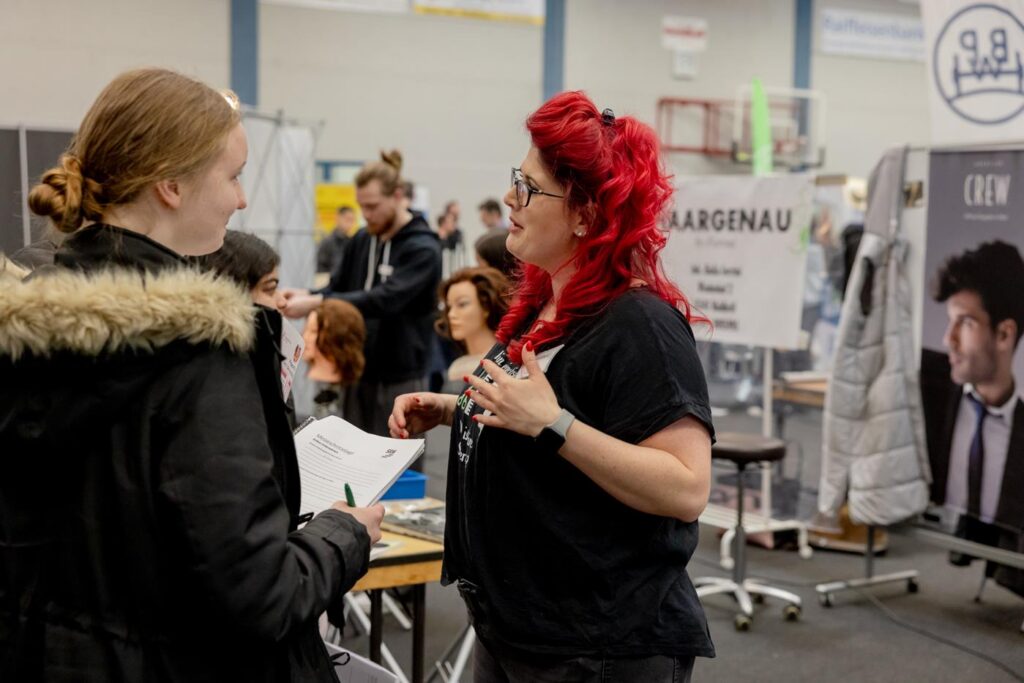 Zwei Personen unterhalten sich auf einer Veranstaltung in einer Halle.