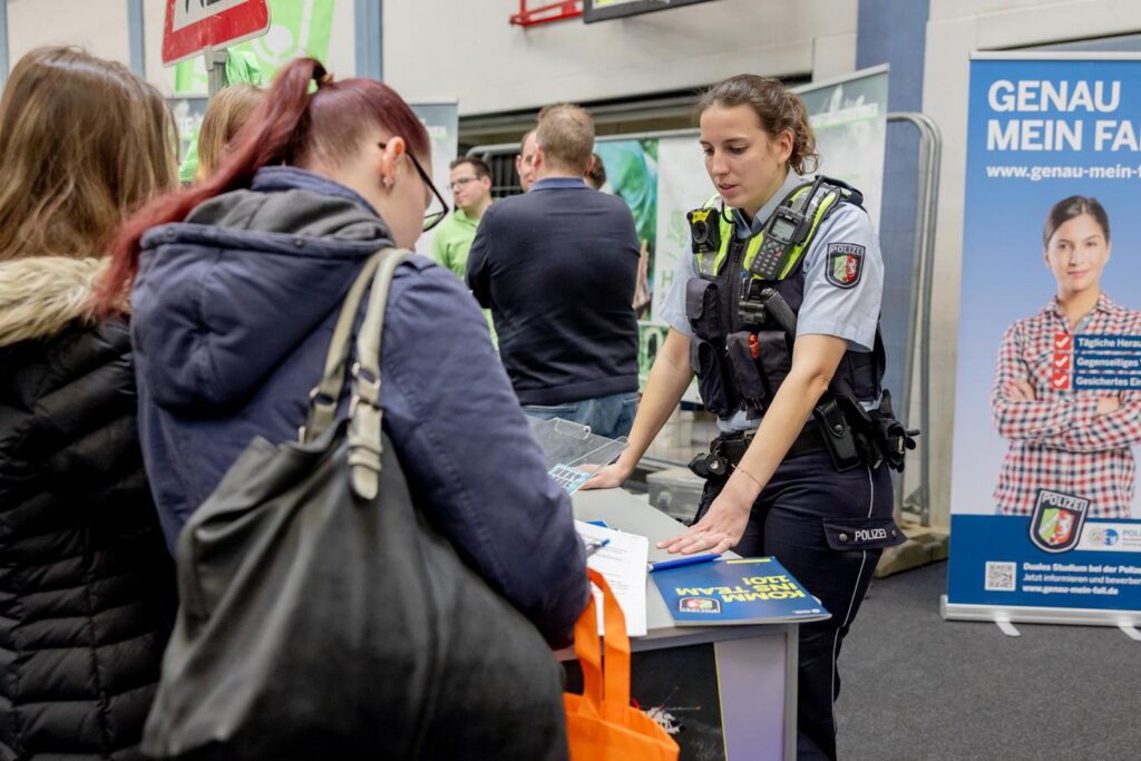 Polizistin berät Besucher an einem Infostand.