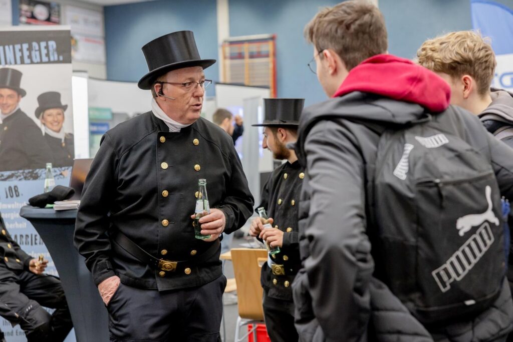 Personen in historischen Anzügen unterhalten sich auf einer Veranstaltung.