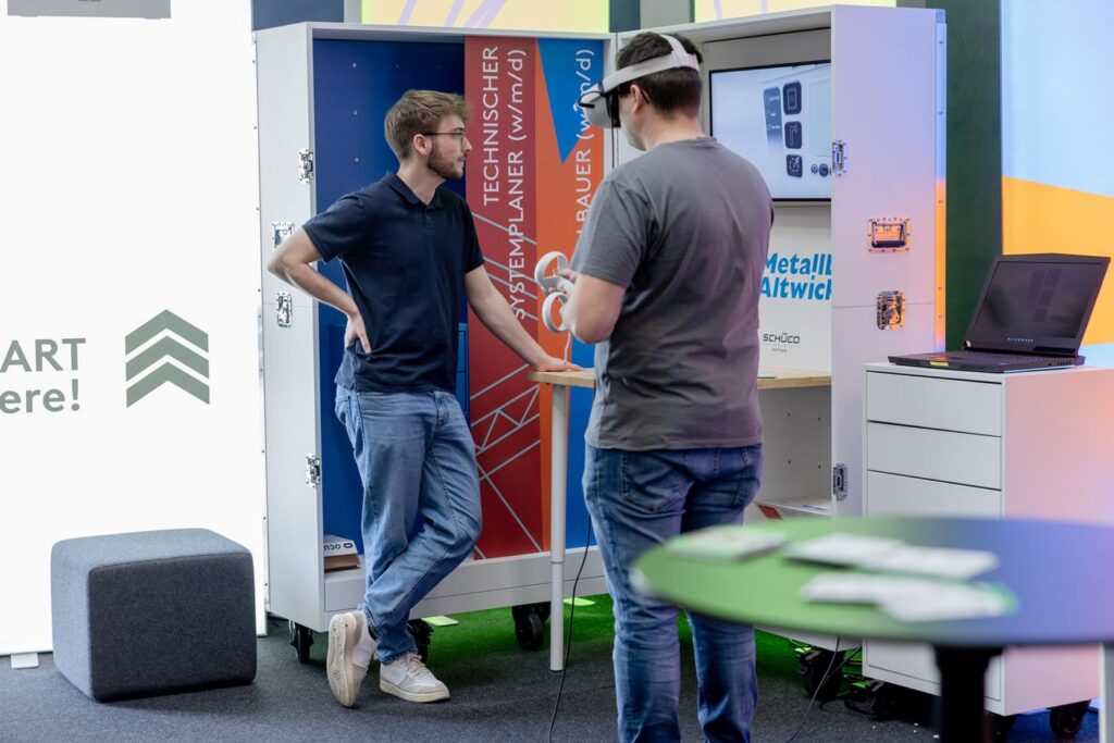 Zwei Personen an einem Stand mit VR-Brille und Ausstellungsmodulen.