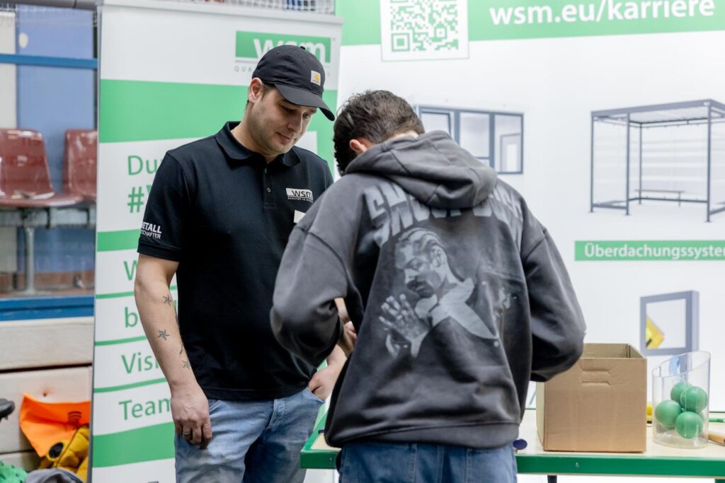 Zwei Personen stehen an einem Stand mit Karriereinformationen.