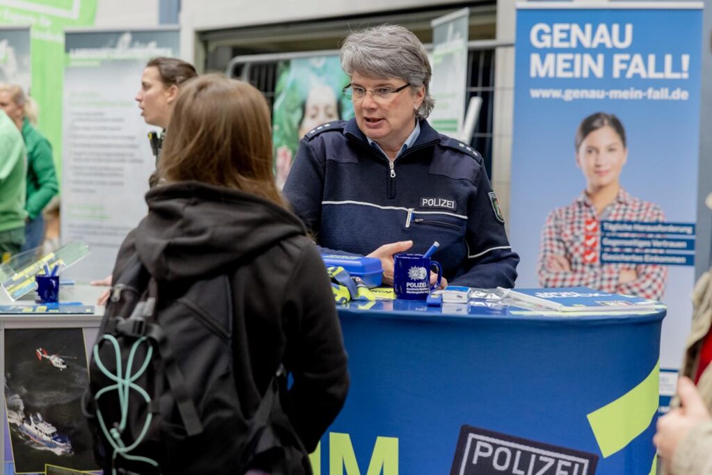 Eine Person am Polizeistand spricht mit einer Besucherin.