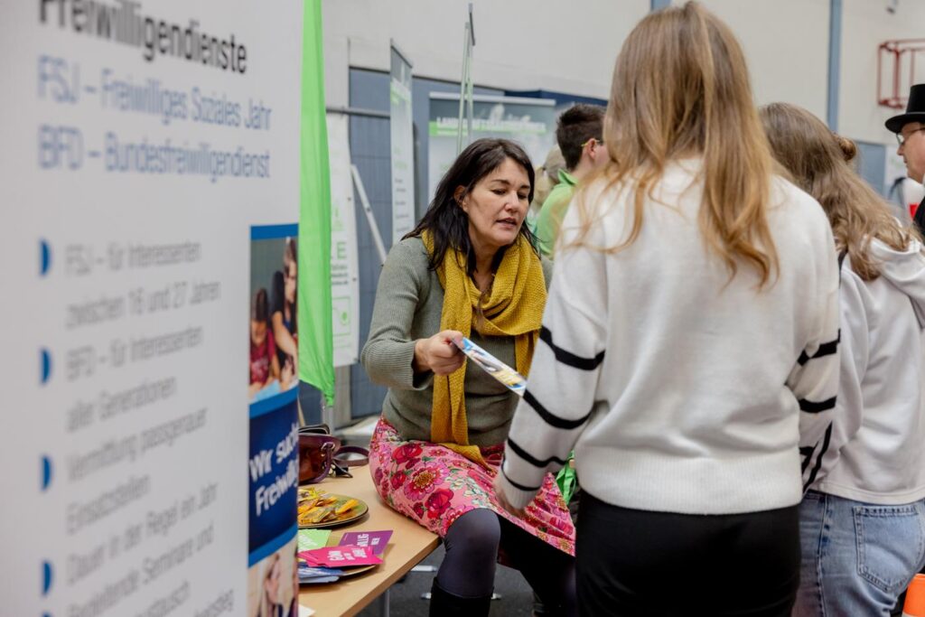 Frau berät Schüler an einem Messestand über Freiwilligendienste.