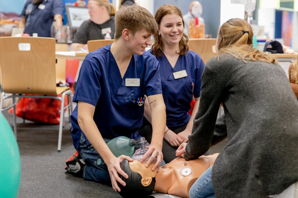 Schüler üben an einer Übungspuppe Erste Hilfe und Wiederbelebung.
