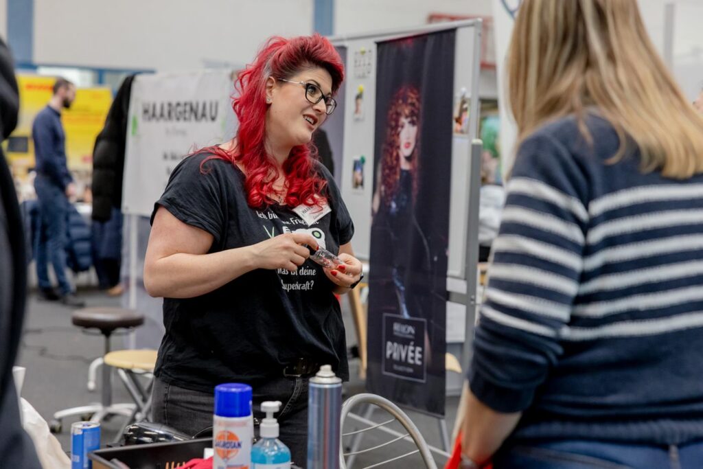 Frau mit roten Haaren spricht mit Besucher am Messestand.