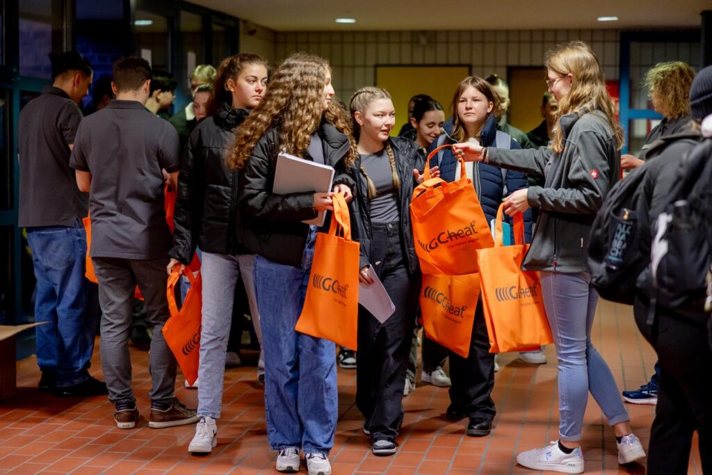 Gruppe von Schülerinnen und Schülern mit orangefarbenen Taschen in einem Flur.