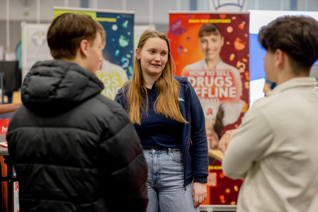 Schüler sprechen mit einer jungen Frau an einem Informationsstand.