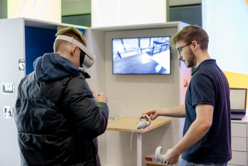 Zwei Personen testen virtuelle Realität an einem Ausstellungststand.