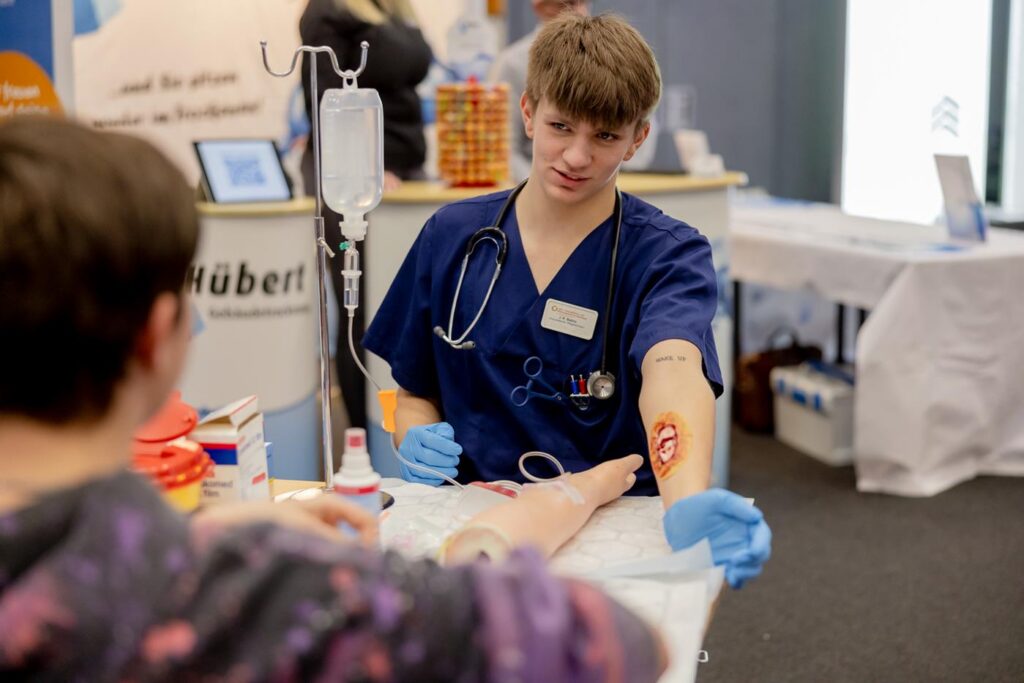 Ein Junge in blauer Arztkleidung verabreicht einem anderen eine Infusion.