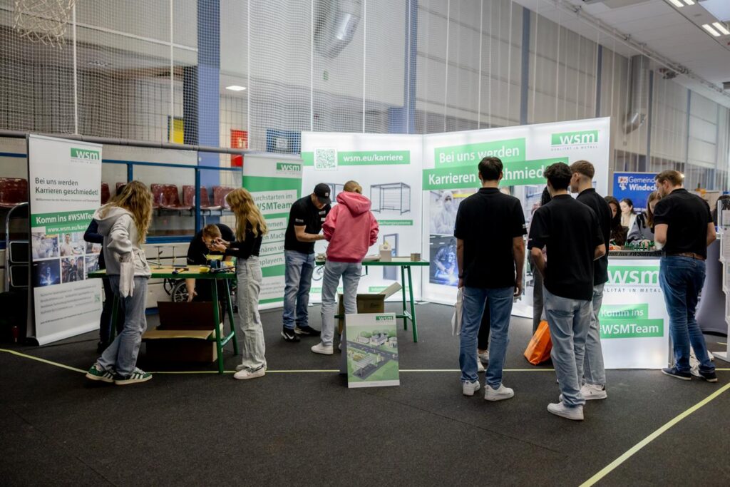 Schülerinnen und Schüler an einem Messestand mit Informationen zu Karrieren.