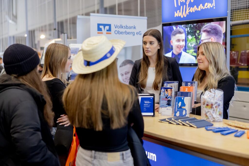 Zwei Frauen am Messestand sprechen mit drei Besucherinnen.