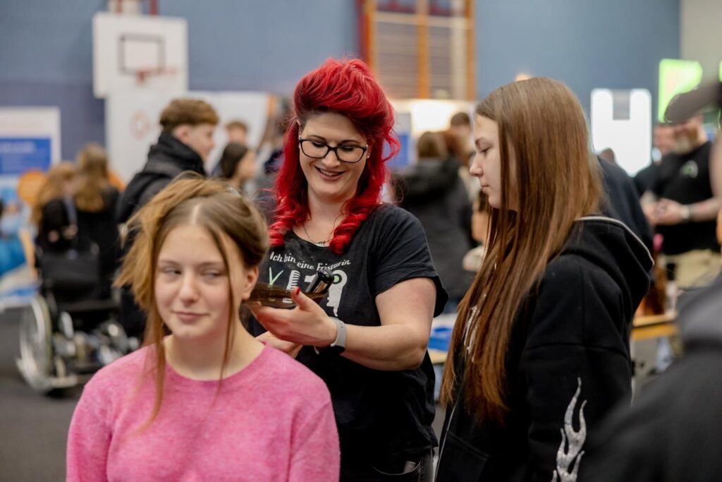 Friseurin schneidet Haare einer Schülerin in einer Schulveranstaltung.