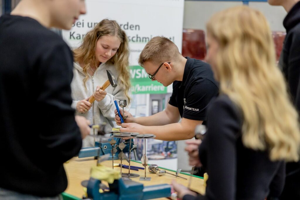 Schüler arbeiten gemeinsam an einer technischen Aufgabe in einer Werkstatt.