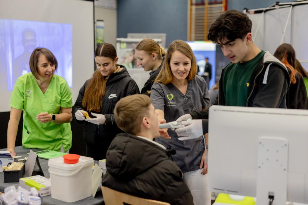 Schüler erhält zahnmedizinische Anleitung von Fachkräften an einem Stand.