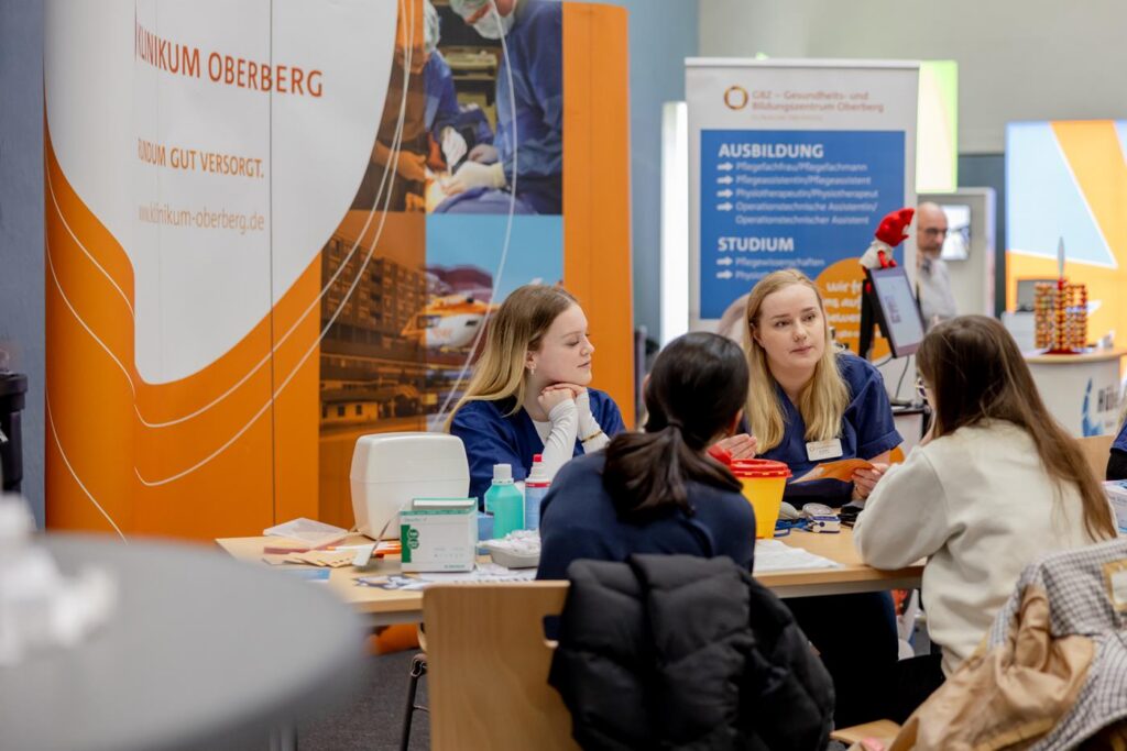Messestand mit Personen im Gespräch und Informationsmaterial.