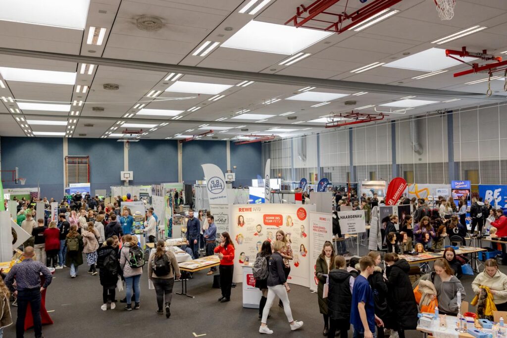 Messehalle mit vielen Ständen und Besuchern bei einer Veranstaltung.