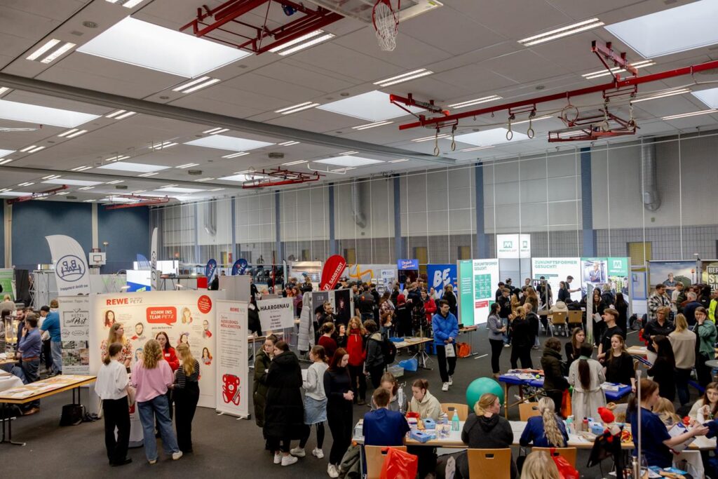 Blick auf eine große Messe mit vielen Ständen und Besuchern.