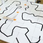 Eine Tischfläche mit einem schwarz umrandeten Labyrinth aus weißen Platten.