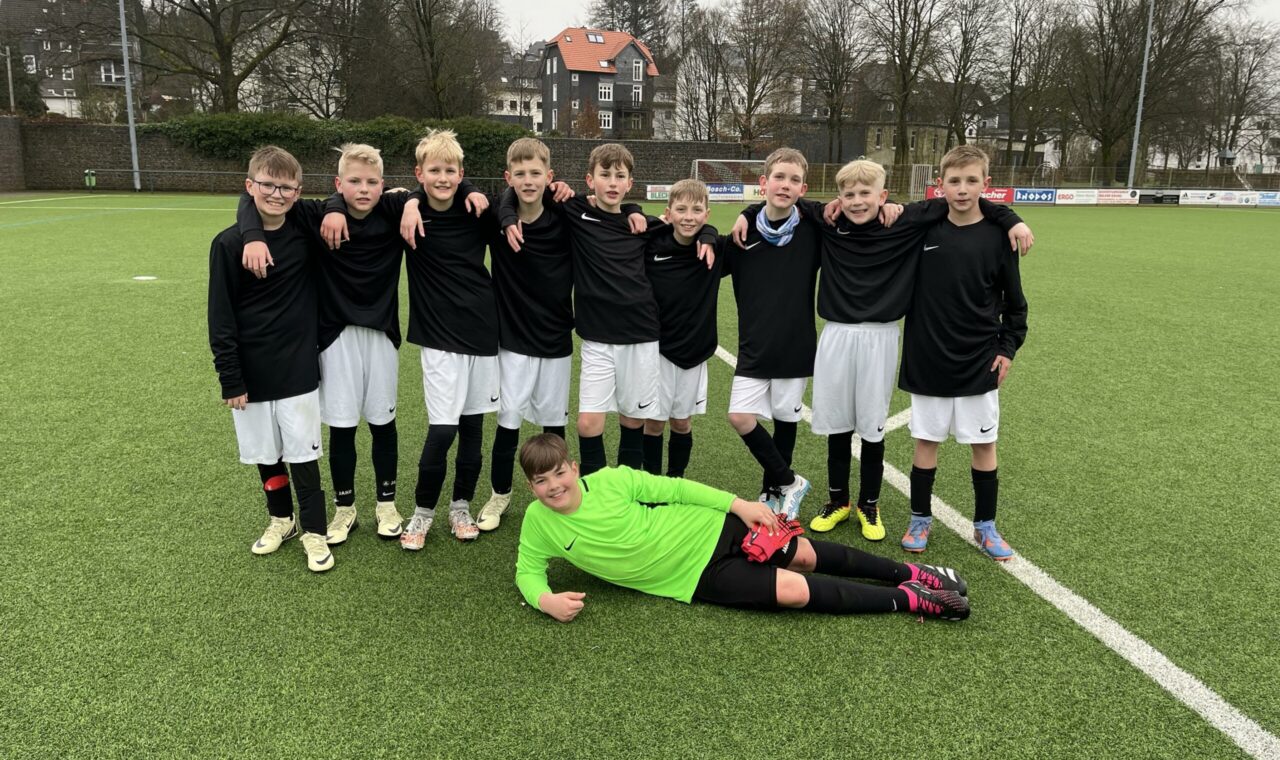 Eine Fußballmannschaft steht auf dem Platz, ein Spieler liegt im Vordergrund.