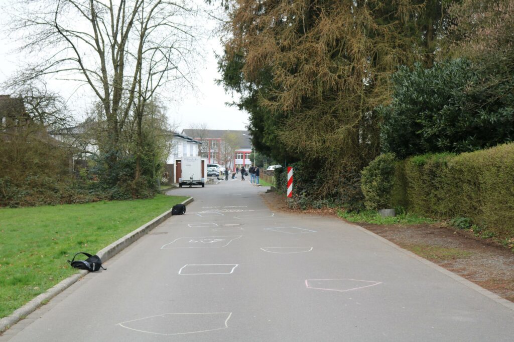 Blick auf eine Straße mit Umrissen, Bäumen und entferntem Personengruppen.