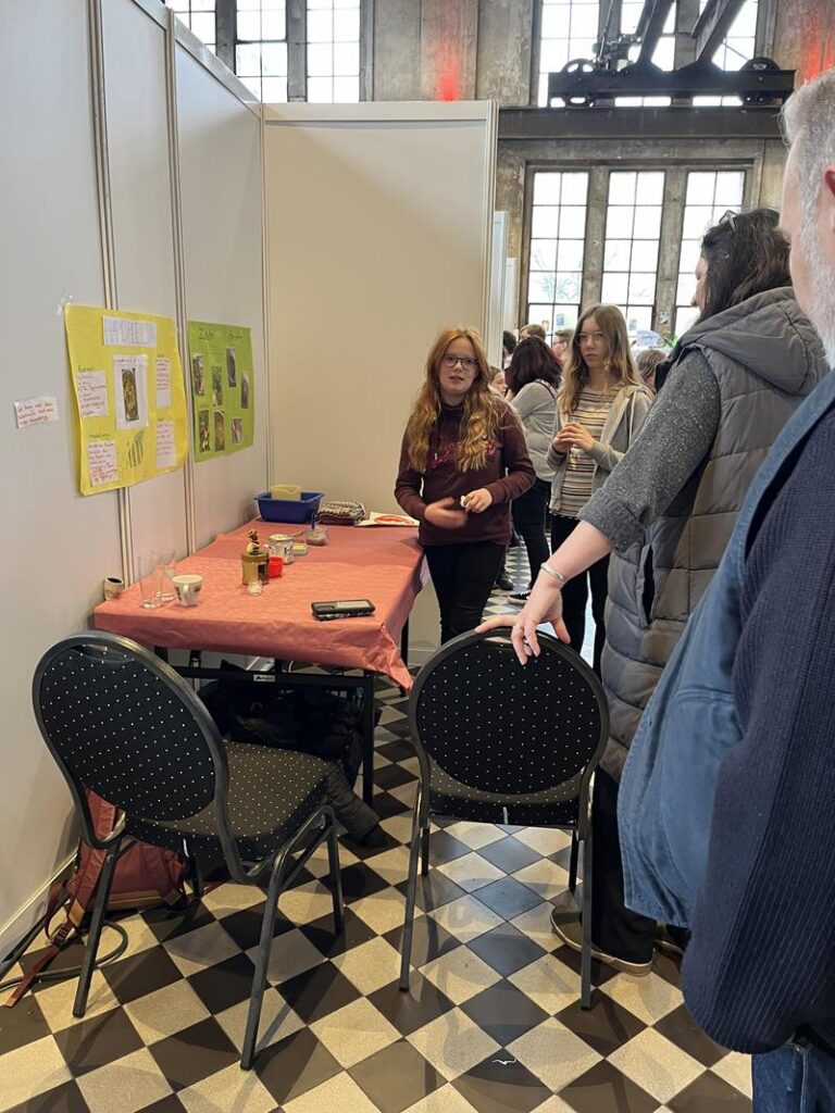 Ein Stand mit Tischen und Stühlen, Besucherinnen stehen und sprechen.