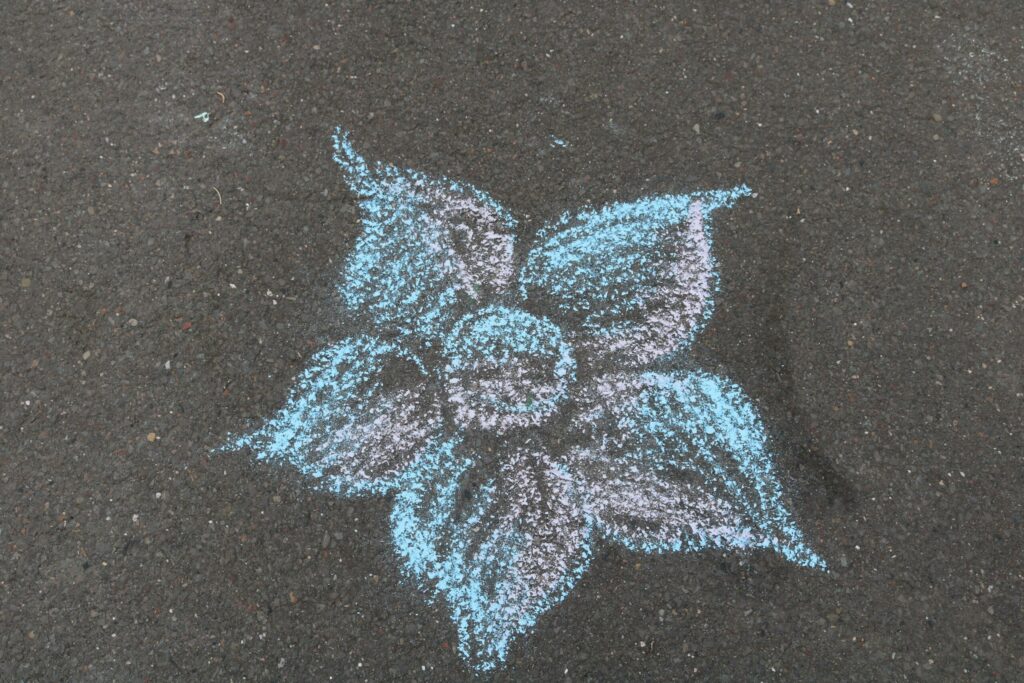 Bunte Blume aus Kreide auf dunklem Asphalt gezeichnet.