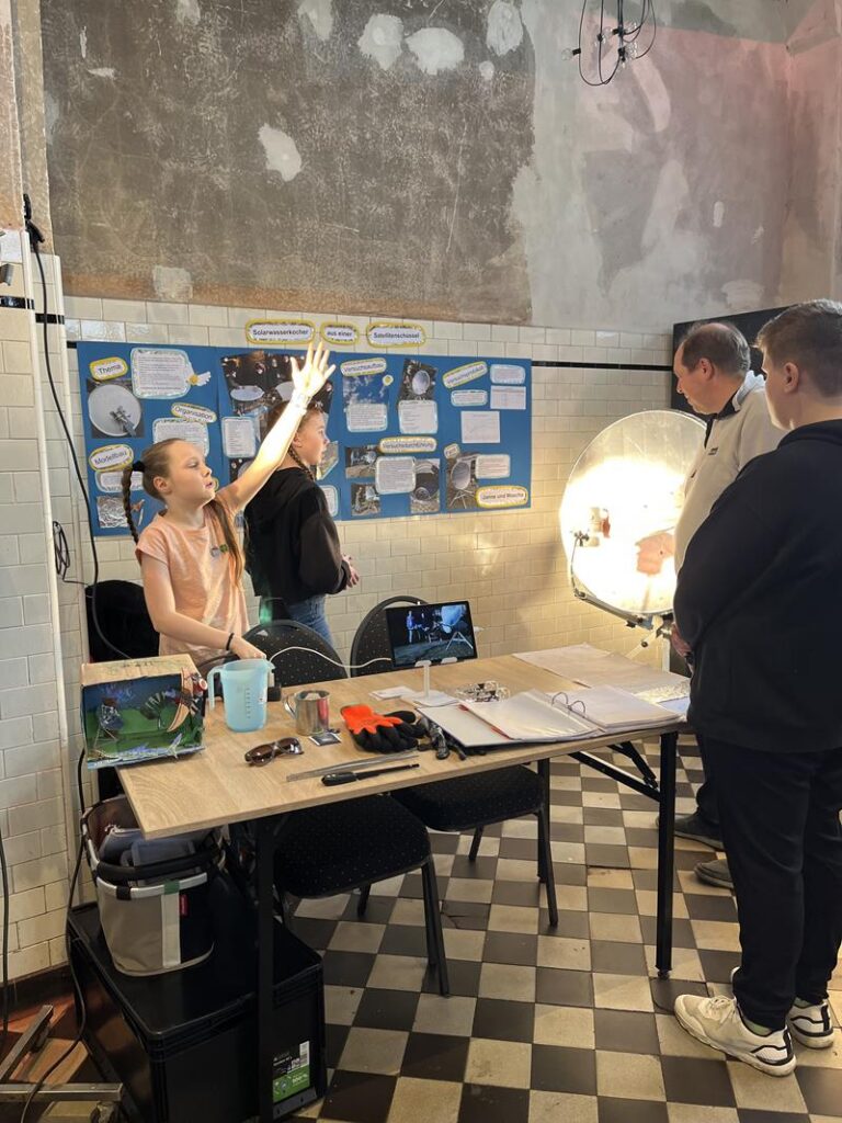 Schüler präsentieren ein Projekt an einem Tisch in einem Klassenzimmer.