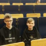 Zwei Schüler sitzen in einem Klassenraum auf Stühlen.