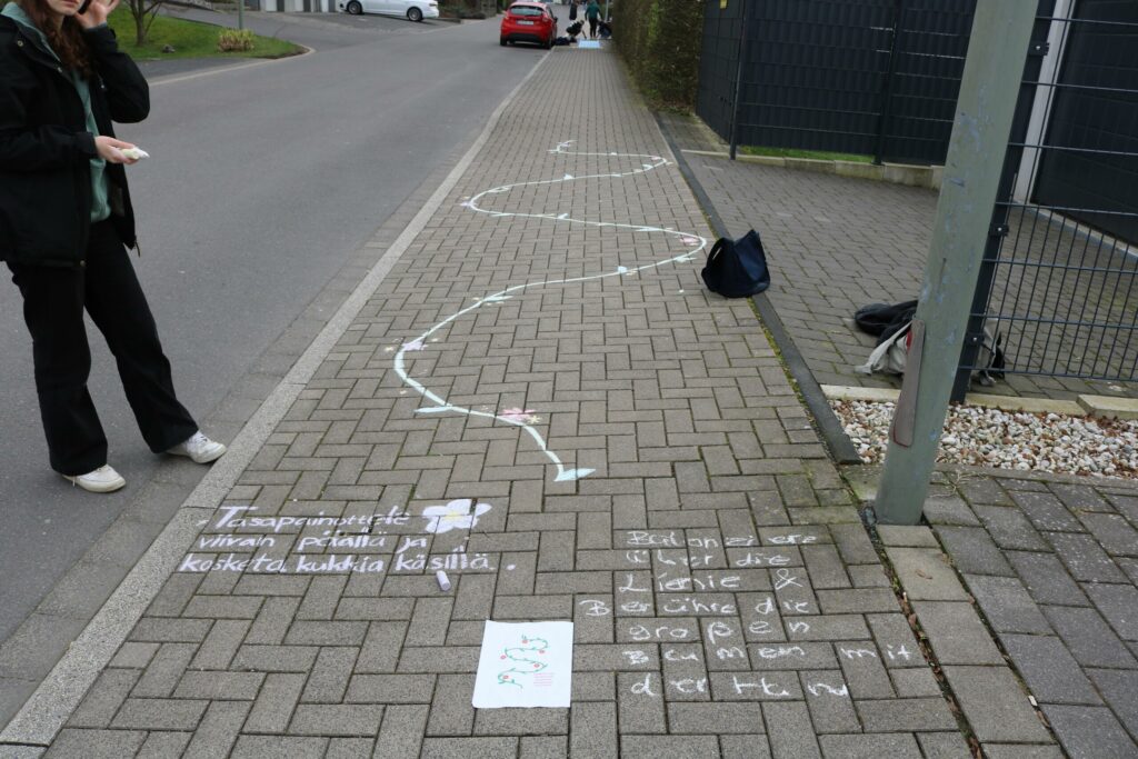 Jemand steht an einem Gehweg mit Straßenkreidezeichnungen.