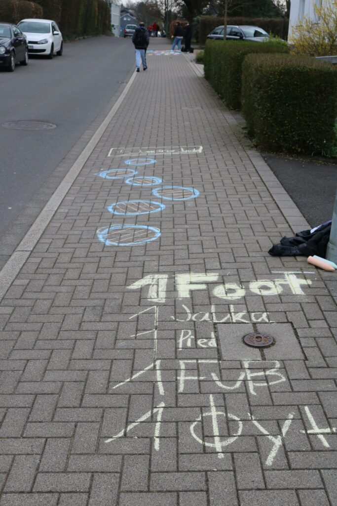 Kreidezeichnungen mit verschiedenen Maßen auf dem Gehweg.