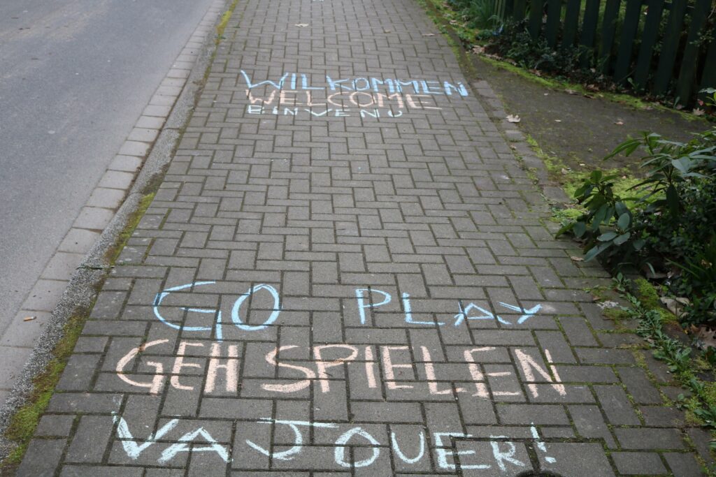 Bunte Kreideaufschriften auf einem Pflasterweg.