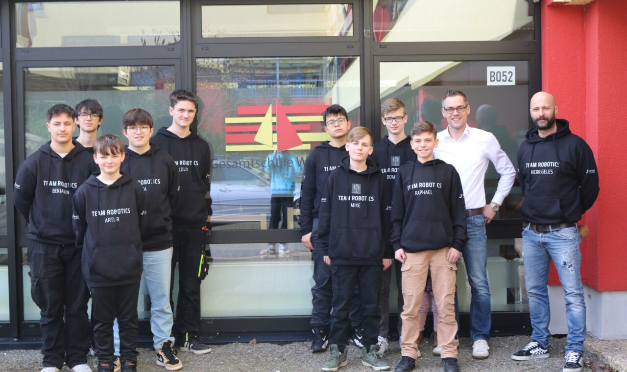 Gruppe von Schülerinnen und Schülern in Sweatshirts vor einem Gebäude.