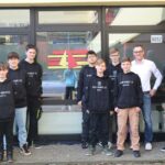 Gruppe von Schülerinnen und Schülern in Sweatshirts vor einem Gebäude.