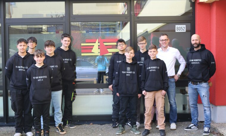 Gruppe von Schülerinnen und Schülern in Sweatshirts vor einem Gebäude.