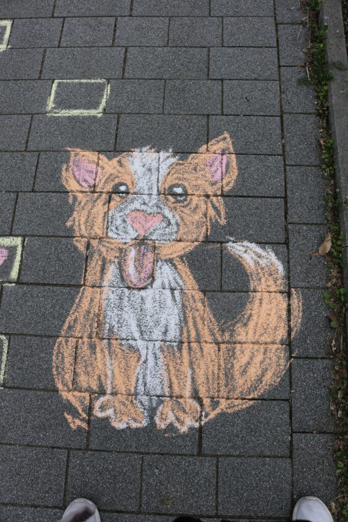 Buntes Straßenkreidebild eines niedlichen Hundes auf einem Gehweg.
