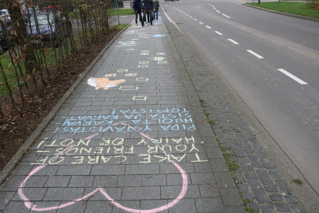 Bunte Kreidezeichnungen und Sprüche auf einem Gehweg.