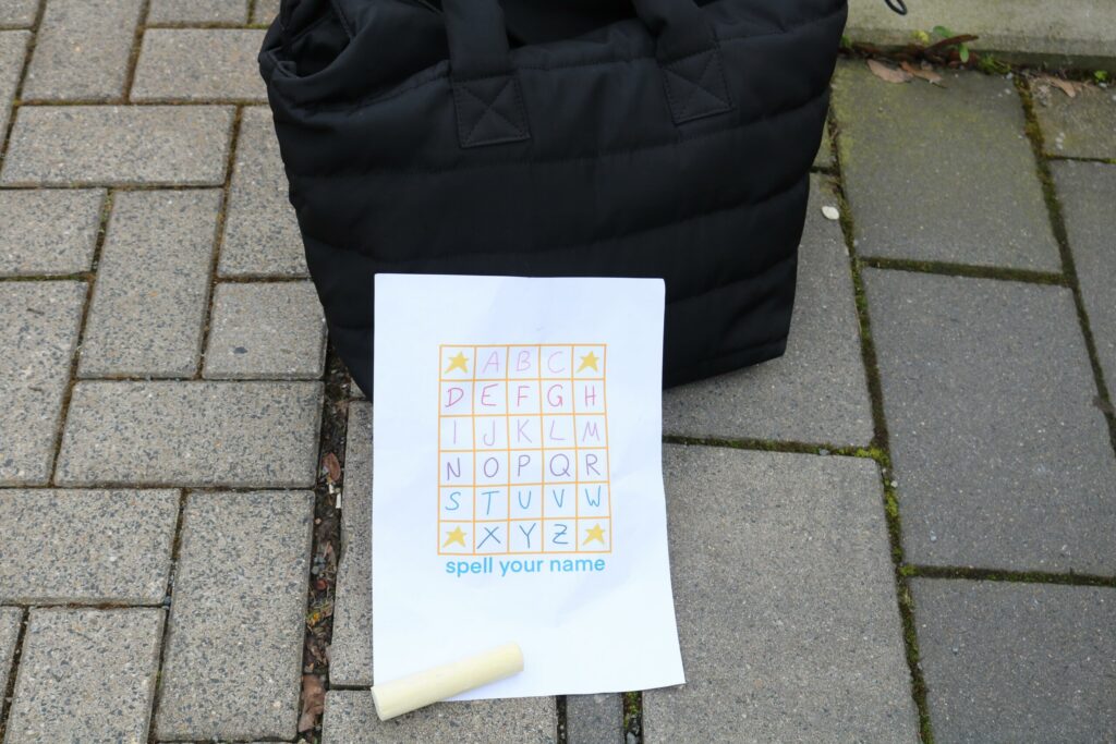 Schwarze Tasche und Blatt mit Buchstabenraster auf dem Boden.