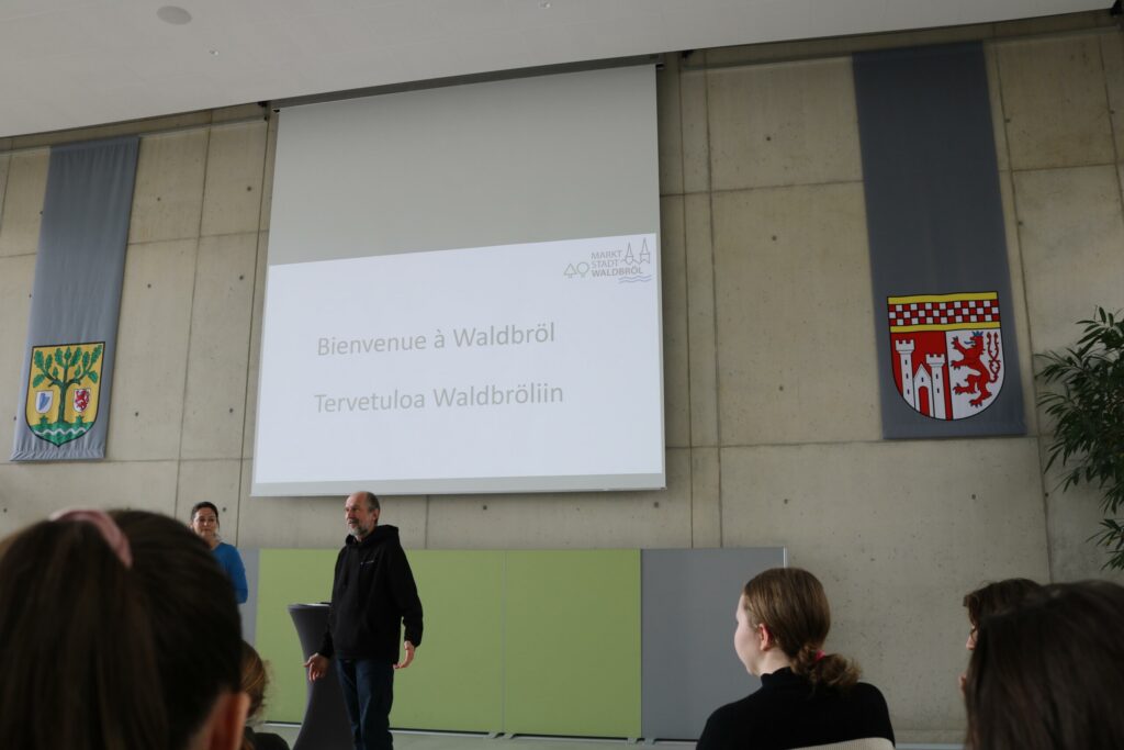 Präsentation in einem Schulraum mit zwei Personen vor einer Leinwand.