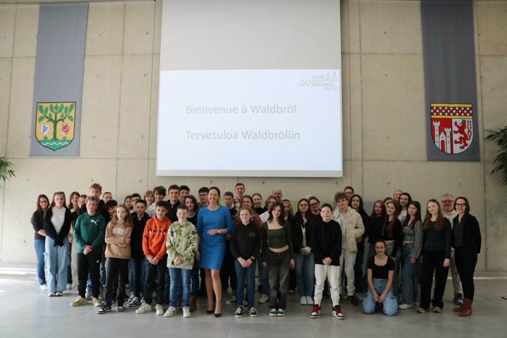 Gruppenfoto von Schülern und Lehrern in einer großen Halle mit Bannern.