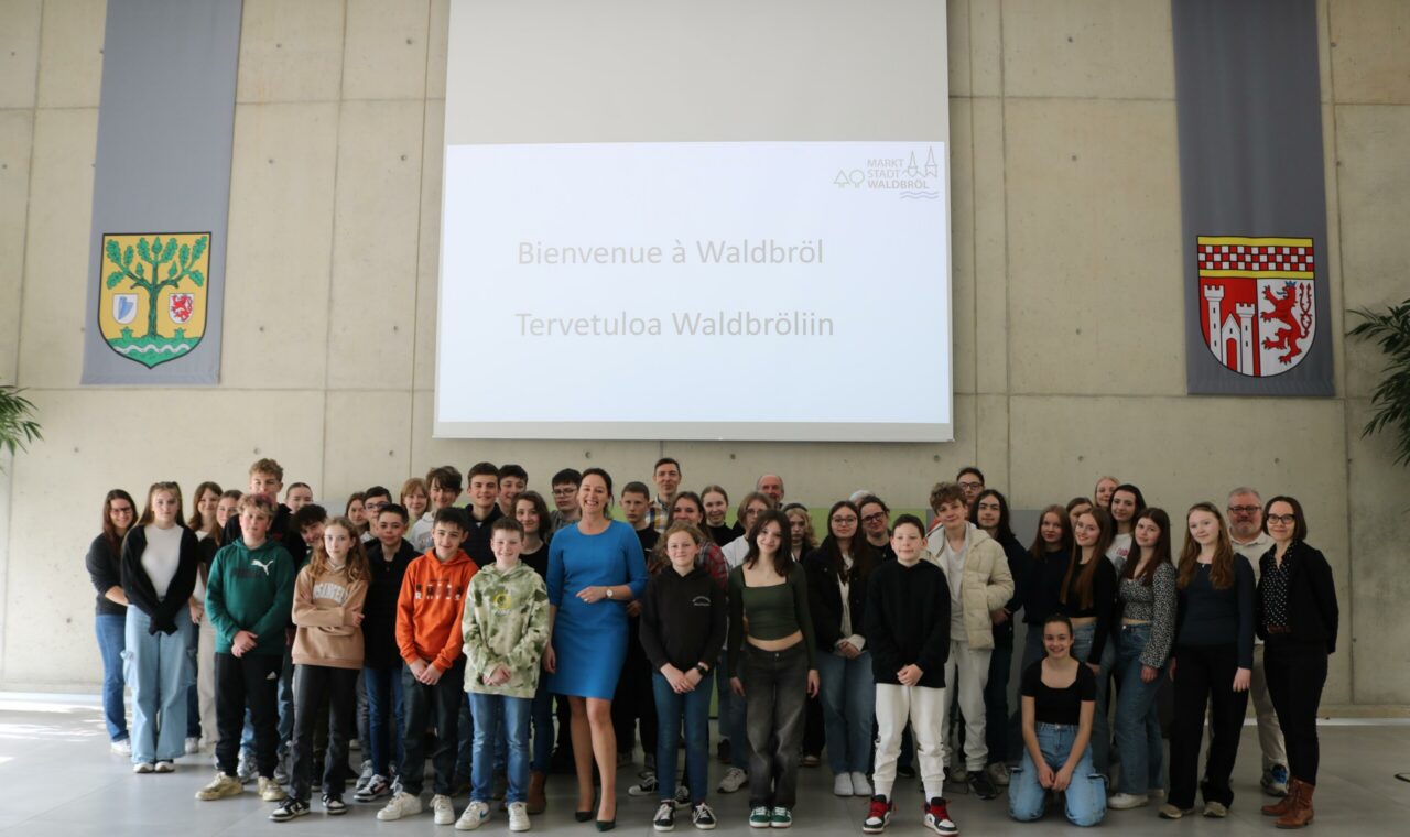 Gruppenfoto von Schülern und Lehrern in einer großen Halle mit Bannern.