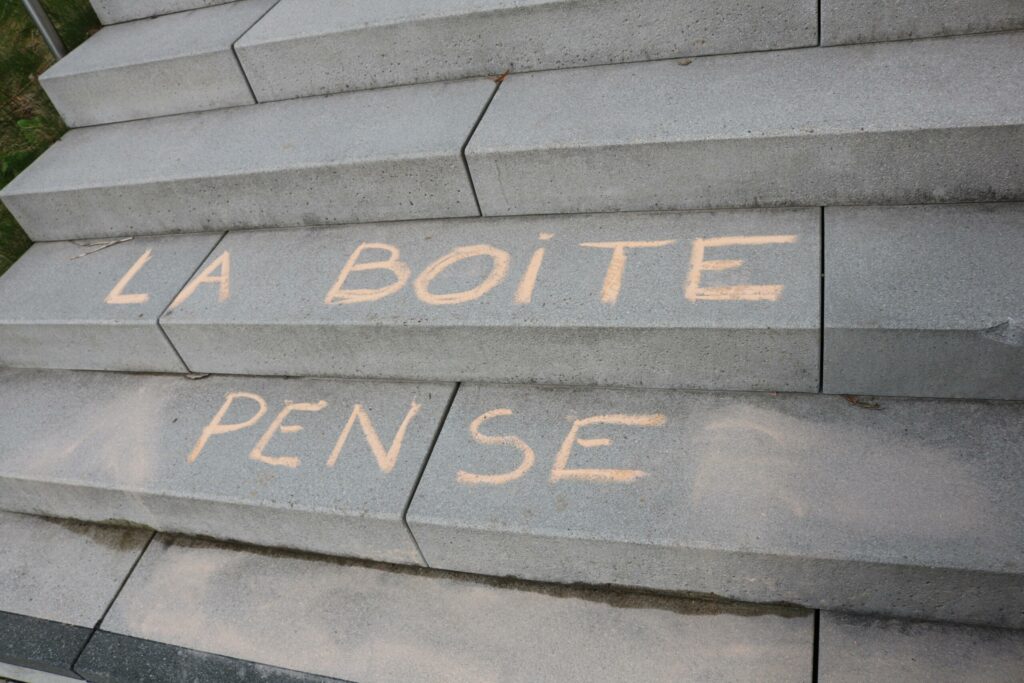Schriftzüge „LA BOîte PENSE“ auf Treppen aus grauem Stein.