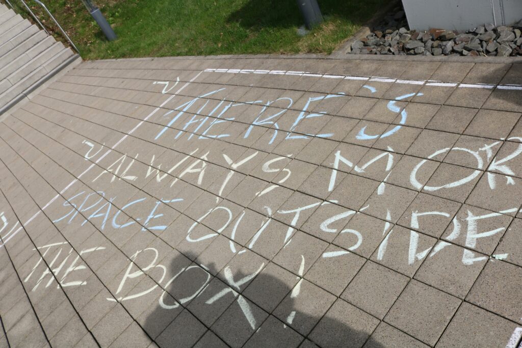 Boden mit buntem Kreideschriftzug: "There's always more space outside the box!