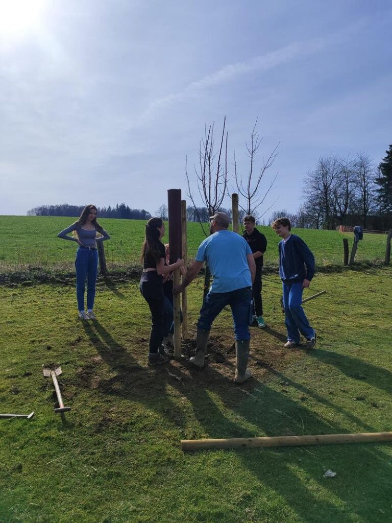 Gruppe von Personen bei der Arbeit an einem Zaunpfosten im Freien.